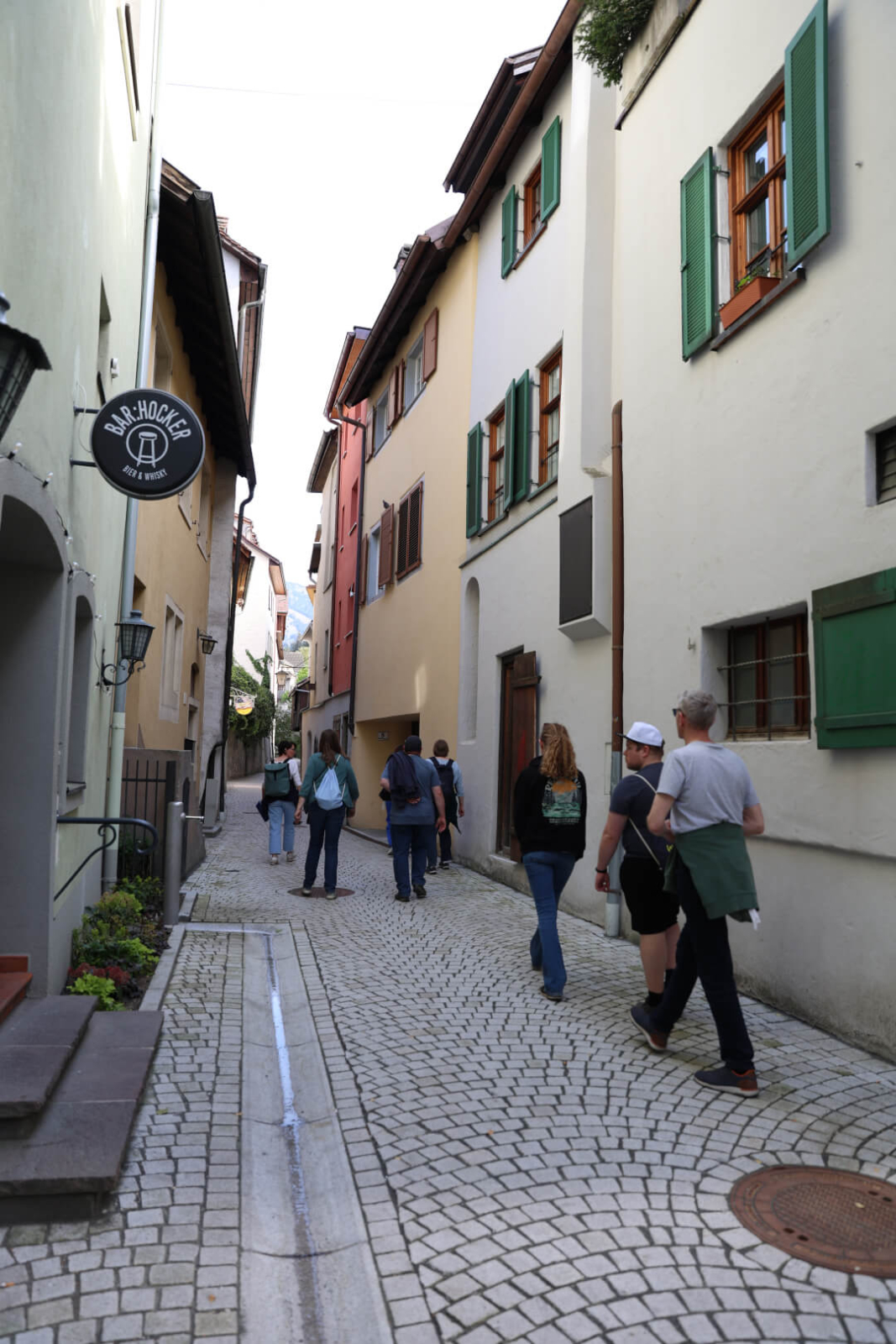 Mehrere Personen gehen durch eine Gasse, angeführt von einer Person